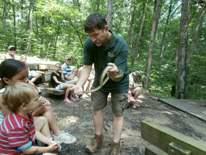 a park naturalist shows two kids a snake
