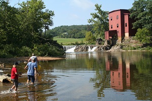 a boy fishing in the water in front of the mill