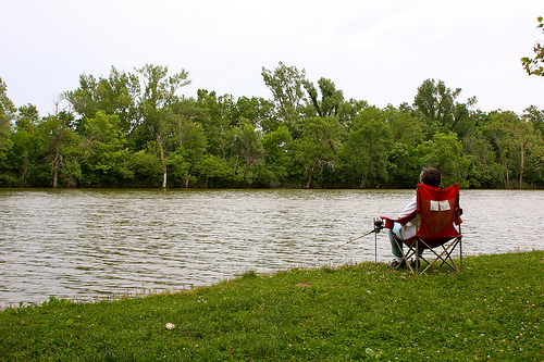 person in lawn chair fishing for the shore of the lake