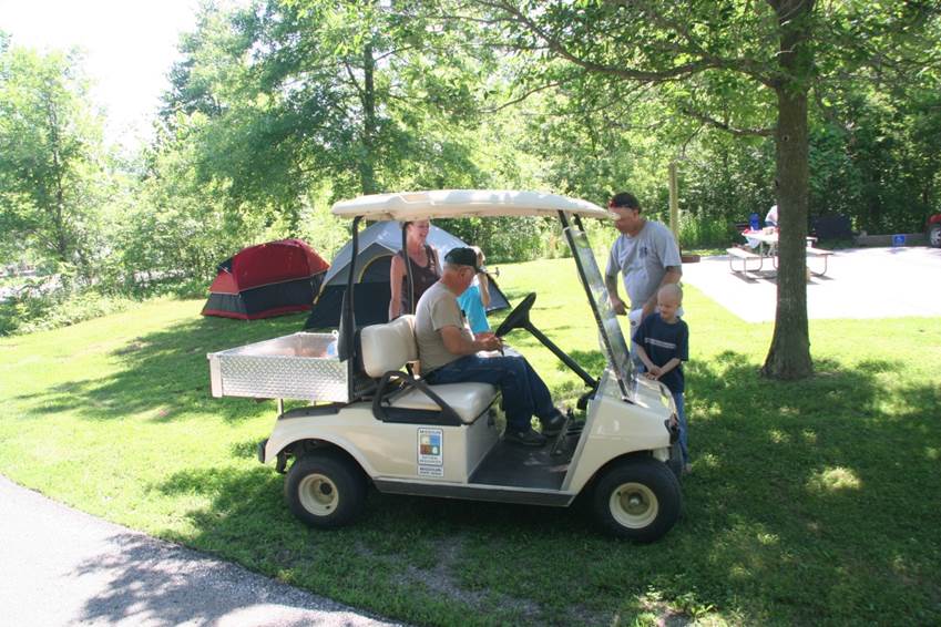 a campground host in his golf cart assisting some campers