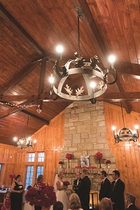 a wedding taking place in the rustic lodge with wood ceiling and rock fireplace