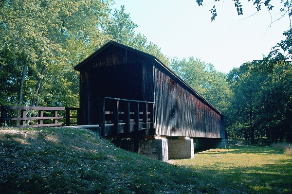 wooden covered bridge spanning a grassy area