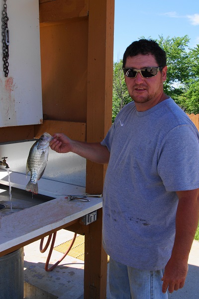 a man holding up a fish at the fish cleaning station