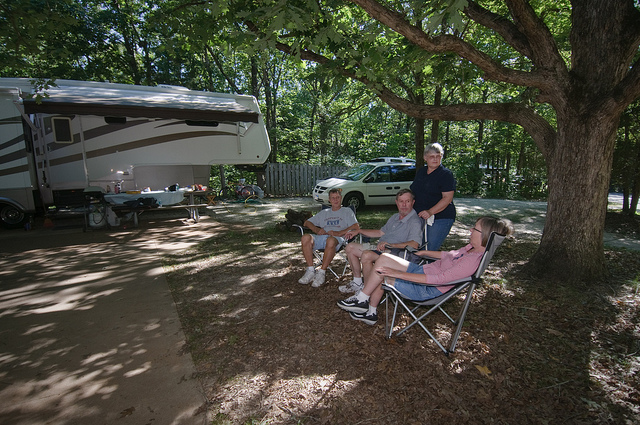 two couples sitting in lawn chairs by their camper