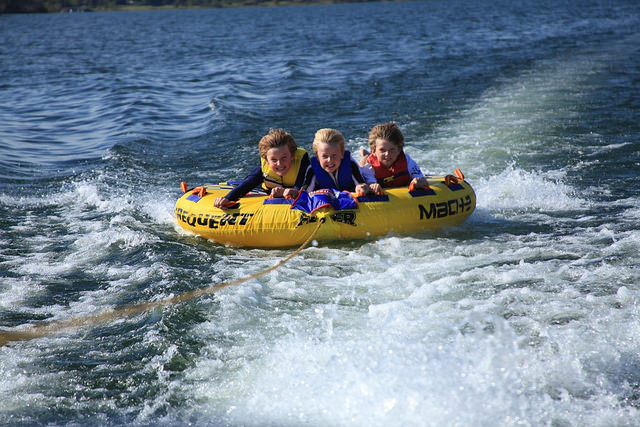 three kids on a tube on the lake