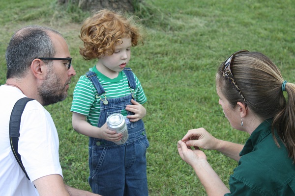 a naturalist shows a small child something in her hands