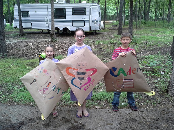 three kids showing off kites they made 