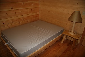 a bed, end table and lamp inside a camper cabin