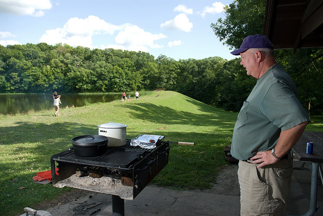 a man watching food cook on a grill