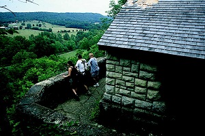three people standing at a stone shelter overlooking the surrounding valley