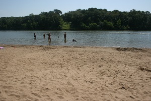 people standing in the water next to the sand beach