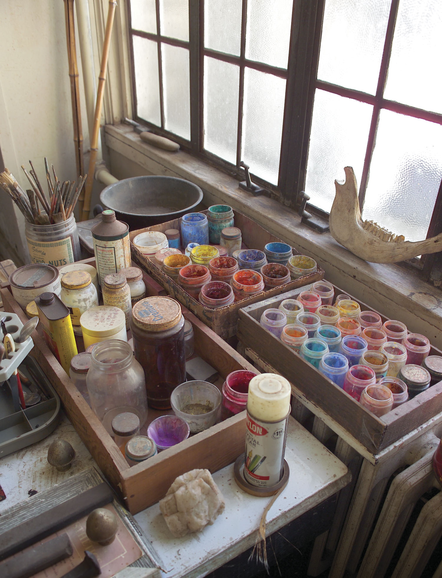 paints sit on a table next to the window in Benton's studio