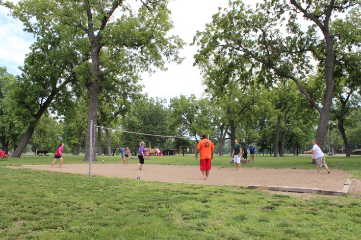 a group playing sand volleyball on the court in the picnic area